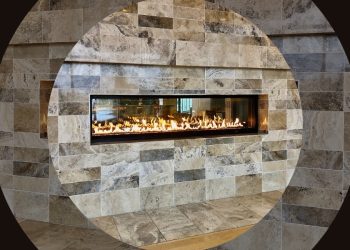 Modern gas fireplace with a sleek glass front, framed by textured stone tiles in neutral colors, creating a cozy and elegant focal point in a contemporary interior.