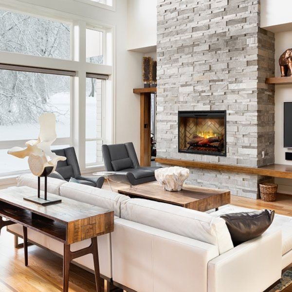 Modern living room featuring a stone fireplace, large windows with a snowy view, contemporary furniture, and wooden accents for a cozy atmosphere.