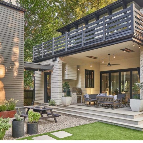 Modern home exterior featuring a spacious patio with outdoor seating, a grill, and decorative plants, surrounded by greenery and soft lighting.