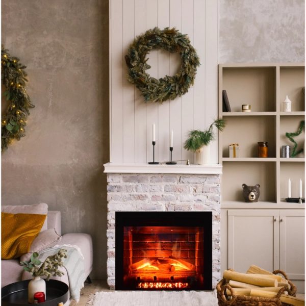 Cozy living room with a modern fireplace, decorated with seasonal wreaths, candles, and a stylish shelf displaying various decor items.